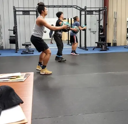 three young men workout using weighted balls