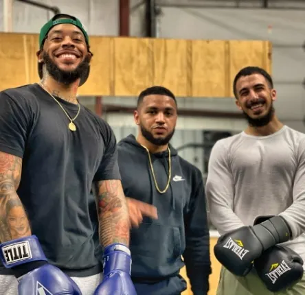 three men pose with boxing gloves on their hands