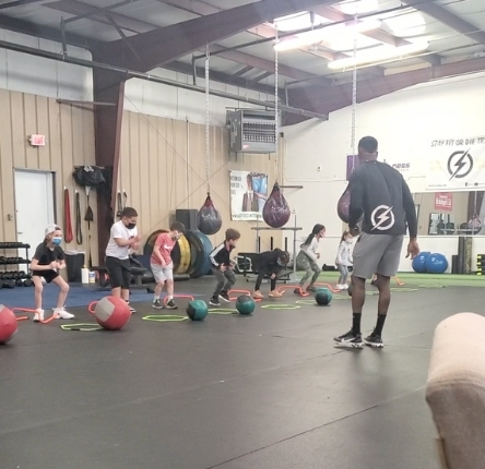 young kids work out using rings and heavy weight balls